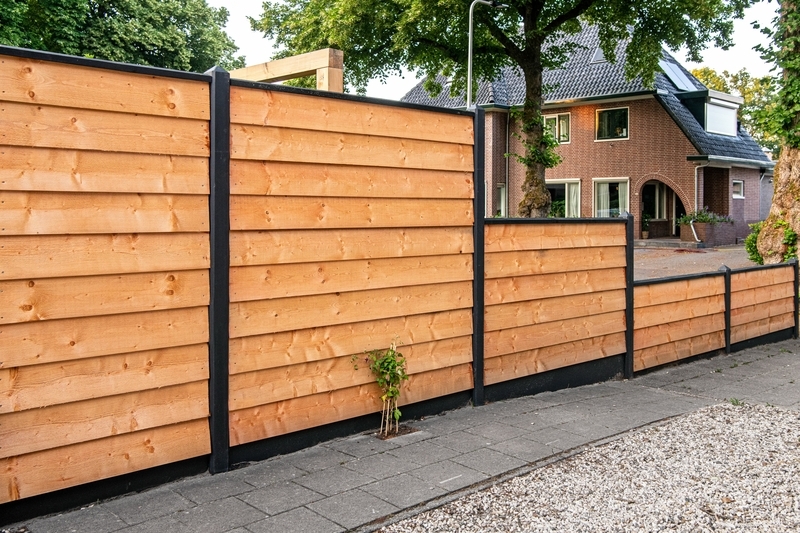 Betonschutting met verticale douglas planken uitgevoerd met gecoate zwarte betonpalen