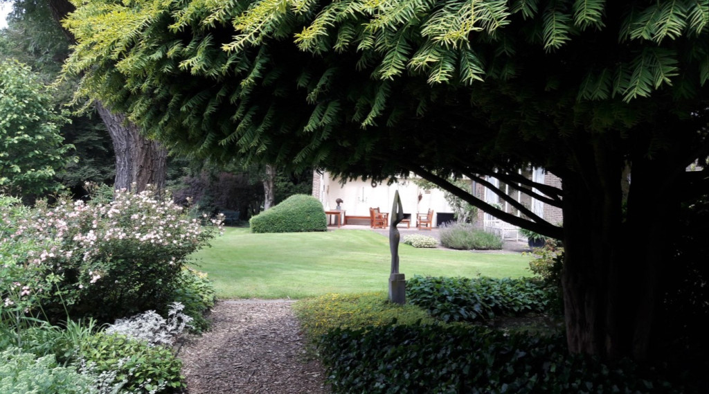 Afbeelding bij Tuin landgoed De Hertgang Engelse landschapsstijl met gazons, borders, vijvers, een ommuurde tuin en bosaanplant.